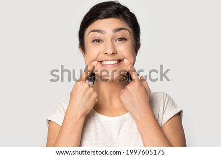 Headshot portrait of overjoyed Indian woman isolated on grey studio background show wide smile. Profile picture of happy young mixed race female feel optimistic excited. Humor, fun concept. Royalty-Free Stock Photo #1997605175