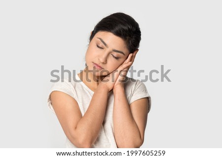 Tired young Indian woman isolated on grey studio background feel fatigue fall asleep take nap. Exhausted millennial mixed race female daydream, asleep on hands. Exhaustion, relaxation concept.