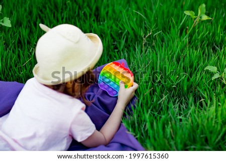 a beautiful girl in a light hat, playing with a toy to drink on the green grass, in the park, on a summer day