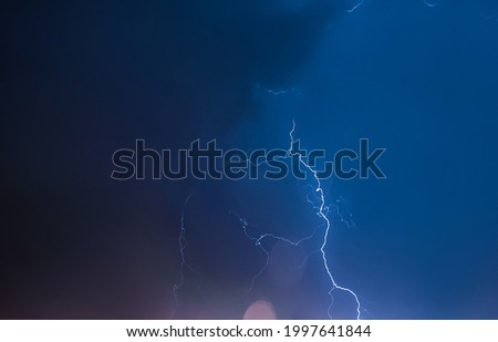 Lightning in the night sky. Thunderstorm over the city. Stormy dark clouds and rainy weather.
