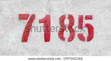 Red Number 7185 on the white wall. Spray paint. Number seven thousand one hundred and eighty five.