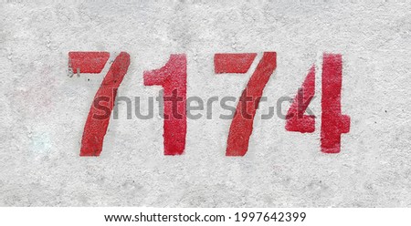 Red Number 7174 on the white wall. Spray paint. Number seven thousand one hundred and seventy four.