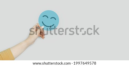 Hand holding blue paper cut happy smile face, positive thinking, mental health assessment , world mental health day concept Royalty-Free Stock Photo #1997649578