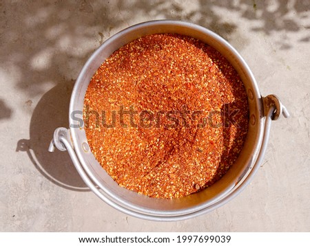 Red hot chili flakes, dried seeds of chili. Pile or collection or group of crushed red Cayenne pepper or hot pepper (Capsicum annuum) in pot. Close-up picture. Top view. Food concept background