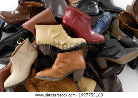 Pile of fashionable different colors leather boots shoes on the floor indoors