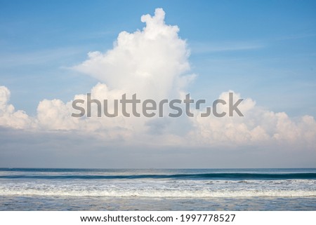 Batu Belig beach (Pantai Batu Belig), Badung, Bali, Indonesia. Grey sand, ocean waves, blue sky with clouds.