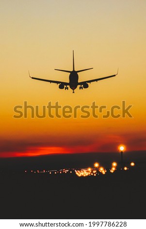 Airplane landing on the runway during sunset and night Royalty-Free Stock Photo #1997786228
