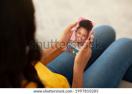 Millennial black mother using cellphone to speak to her lovely teen daughter online from home. Young woman conferencing with her child, sending love remotely, chatting to her kid