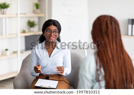 Psychotherapy consultation. Counselor talking to black woman on meeting at office, giving advice to young client. Friendly African American psychologist having session with female customer Royalty-Free Stock Photo #1997810351