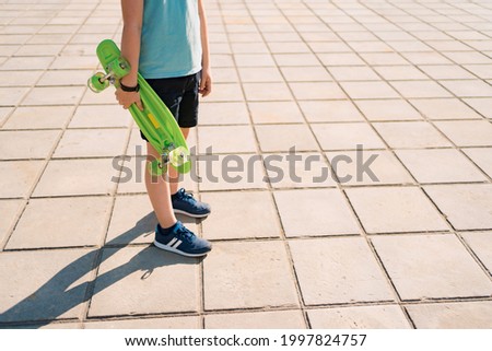 Young SCHOOL cool BOY legs walking with PENNY BOARD in the hands