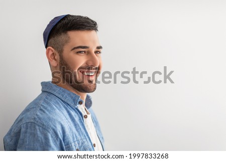 Happy Person. Closeup portrait of handsome cheerful israeli guy posing at studio, smiling and looking aside, wearing yarmulke, posing isolated on light background wall, copy free space, advert banner Royalty-Free Stock Photo #1997833268