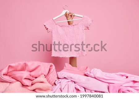 Clothes on sale. Pink t shirt on hangers advertised for selling. Big discounts in retail shop, Monochrome shot. Shopping in clothing store. Unrecognizable human holds apparel. Shopping concept Royalty-Free Stock Photo #1997840081
