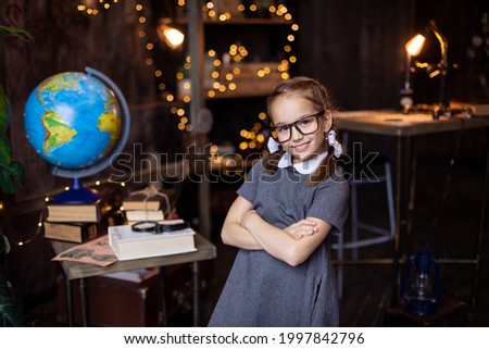 schoolgirl puts on glasses. Back to school concept. A girl typical nerd in a  uniform with pigtails. Primary School. Home work place. Classroom. Hunger for knowledge. Study education. 