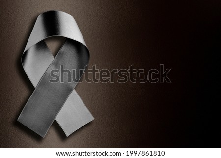 black ribbon symbolizing mourning on a lighted background