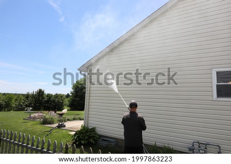 Mold is cleaned from a house using a power washer. Royalty-Free Stock Photo #1997863223