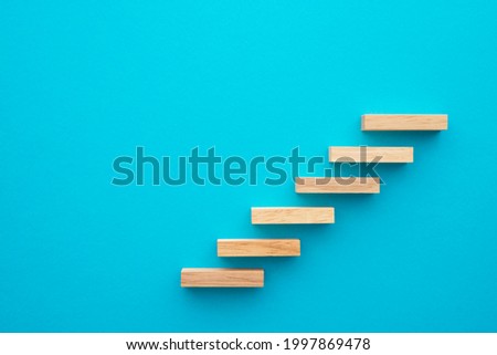Flat lay of wooden blocks in shape of staircase step on blue background with copy space. Growth or development step by step for successful in business financial or education concept. Royalty-Free Stock Photo #1997869478