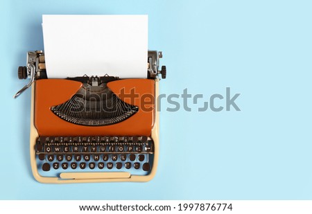 Vintage typewriter on light blue background, top view. Space for text Royalty-Free Stock Photo #1997876774