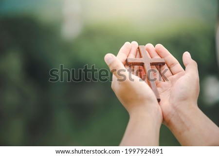 man hands palm up praying and worship of cross with Belief in Jesus Christ. Eucharist therapy god blesses help, hope, and faith, Christian religion concept on sunset background. Royalty-Free Stock Photo #1997924891