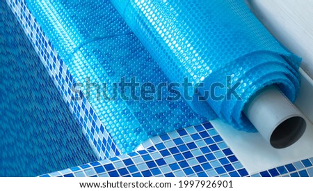 Blue tarpaulin pool cover. Bubble awning wrap for swimming pool cover. Swimming pool with a blue water. Royalty-Free Stock Photo #1997926901