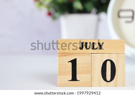 Cube wooden calendar showing date on 10 July. Wooden calendar with date on the table.