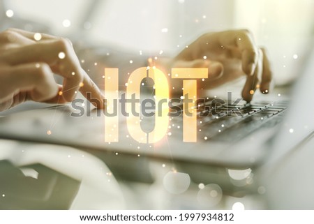 Creative IOT concept with hands typing on laptop on background. Multiexposure