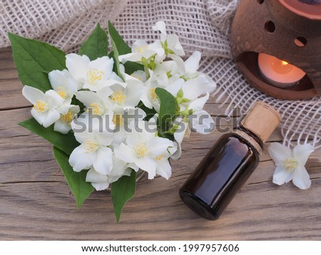 Delicate bouquet of jasmine with white flowers, essential oil, aroma lamp with burning candle on a wooden table with a napkin, top view. Summer flowers of jasminum. Flower romantic picture