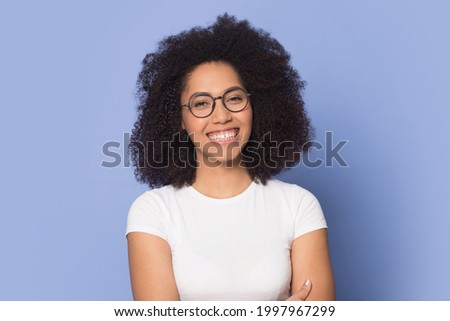 Headshot portrait of smiling African American woman in glasses isolated on blue background. Profile picture of happy millennial biracial female in spectacles have eyesight problem. Optician concept.