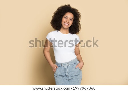 Portrait of smiling young African American woman isolated on yellow studio background wear casual clothes feel optimistic. Happy millennial biracial female show fashion style. Diversity concept.
