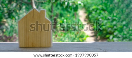 Banner with wooden house on blurry background of garden. Symbol of village life, living in private house, selling suburban real estate.
