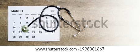 stethoscope with date on calendar page on old wooden table Health care concept.
