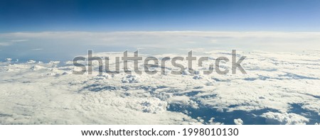 Wallpaper of clouds and mountain peaks from the height of an airplane, side view close-up