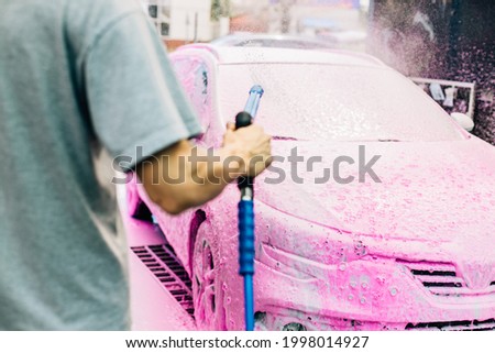 Manual car wash with pressure water on the street, Summer car wash, Car wash with high pressure water, Car wash with pink foam