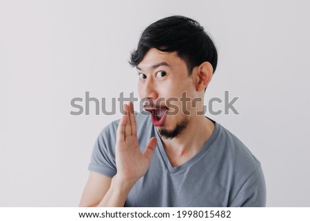 Funny Asian man is whispering some secret gossip isolated on white background. Royalty-Free Stock Photo #1998015482