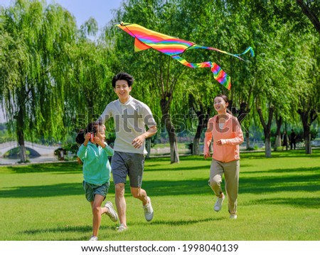 Happy family of three flying kites in the park high quality photo