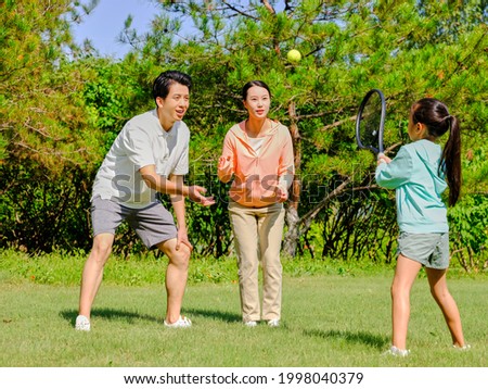 Happy family of three playing tennis in the park high quality photo