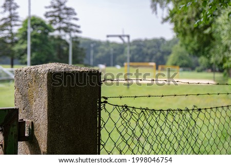 The picture shows a sports field or playground that is cordoned off. Sports field surrounded by the fence. Makes the Corona time well with restrictions.