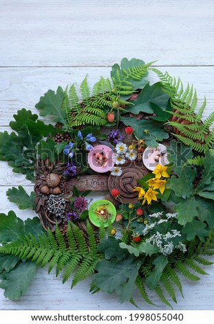 Wiccan Altar for Summer solstice, Litha pagan holiday. wheel of the year with oak, fern leaves, flowers, pentagram, candles on wooden table. symbol of celtic wiccan sabbath, summer season. flat lay Royalty-Free Stock Photo #1998055040