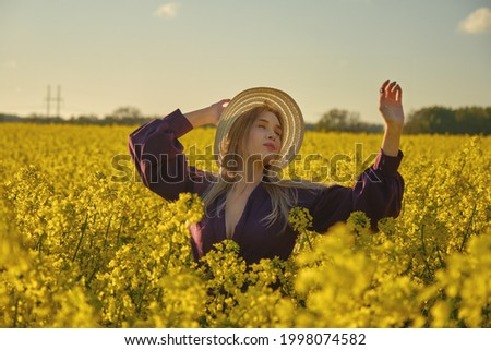 happy young attractive woman in hat and purple dress on rapeseed field