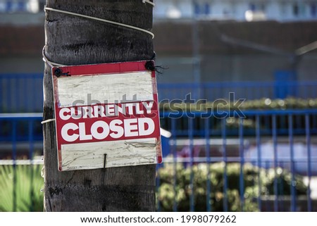 Currently closed sign on tree outside of business
