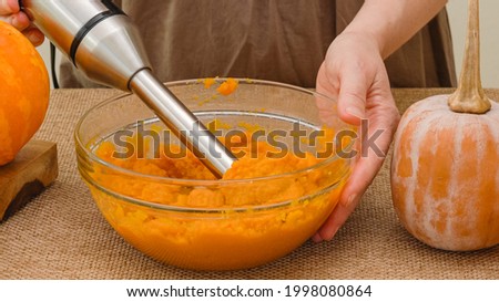 Woman hands making pumpkin puree using an electric blender. Pumpkin puree recipe, lifestyle, rustic backround Royalty-Free Stock Photo #1998080864
