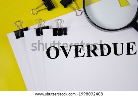 OVERDUE word written on white paper and yellow background with magnifier