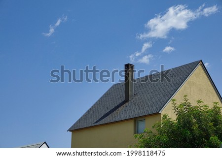 Tall chimney on roof with slate tiles