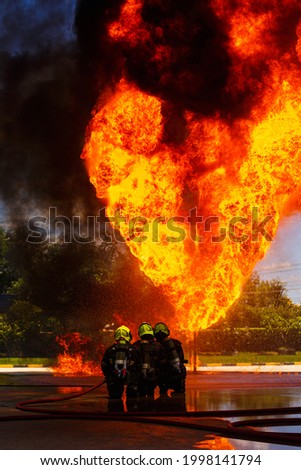 Three firefighter of fireman water spray by high pressure nozzle in fire fighting operation. Fire and rescue training school regularly to get ready. Fire control training station gas pipe leaking
