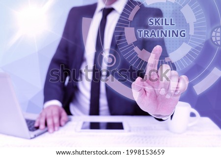 Text sign showing Skill Training. Word for designed to gain and enhance the knowledge an employee needs Bussiness Man Sitting Desk Laptop And Phone Pointing Futuristic Technology.