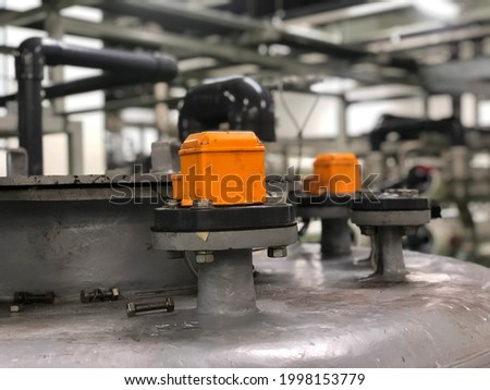 Blurred background level switch, level relay or float switch, a device used to detect the level of water  in a tank, for industrial water treatment plant, out of focus, noise and grain effects.