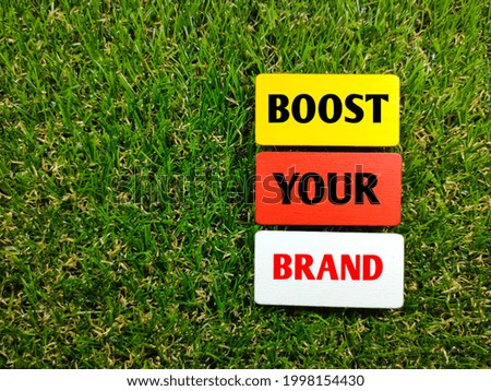 Business concept.Text BOOST YOUR BRAND on wooden board with grass background.