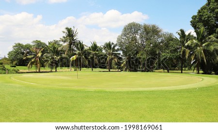 Yellow golf flag on green fairway with beautiful blue sky, with empty copyspace.