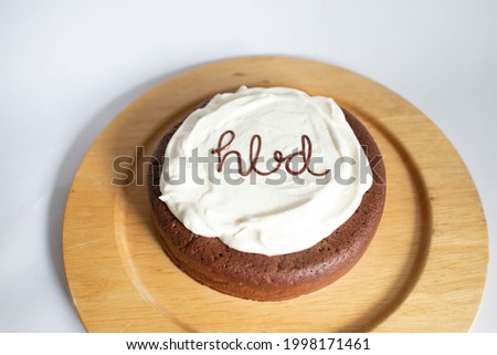 A chocolate birthday cake with cream and writing HBD