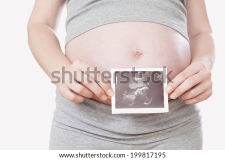 Pregnant woman, holding ultrasonic picture, mid-section