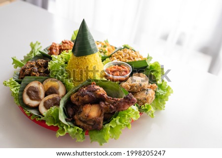 nasi tumpeng. indonesian cuisine yellow rice on banana leaf for celebration Royalty-Free Stock Photo #1998205247